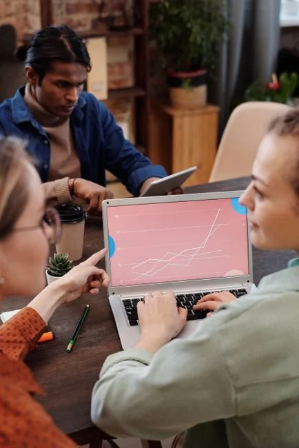 Un espace de travail contemporain où des mains analysent des données marketing sur un ordinateur portable et des documents papier.